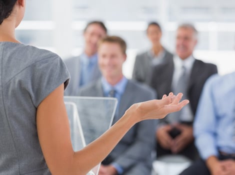 businesswomen making a speech to a group of men