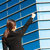 women with fist in the air next to an office building