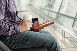 man drinking coffee reading a tablet