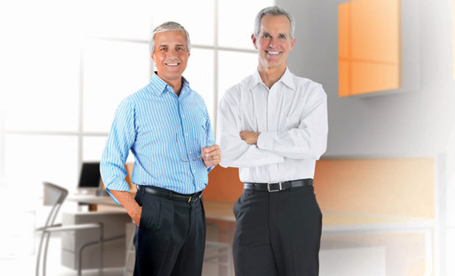 Two business men standing near the office desk.