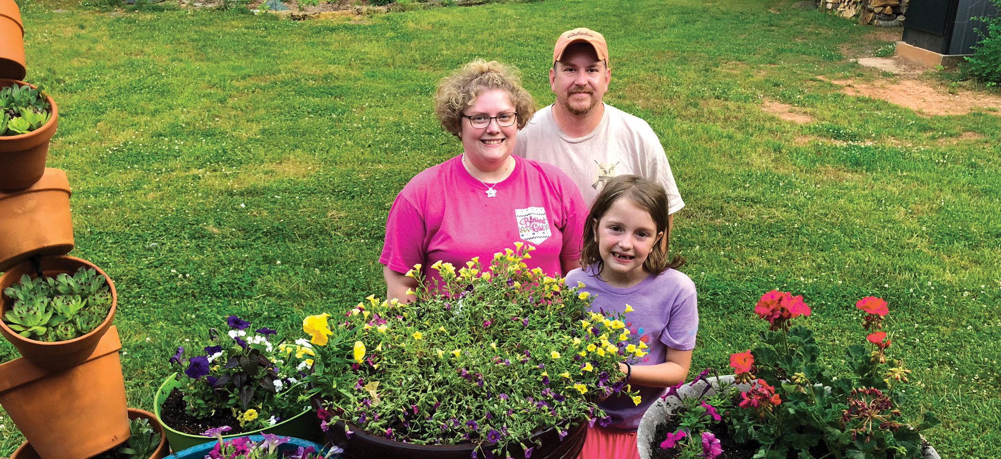 The Langley family stands behind several potted plants