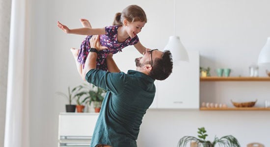 A father holding his daughter in the air with her arms out.